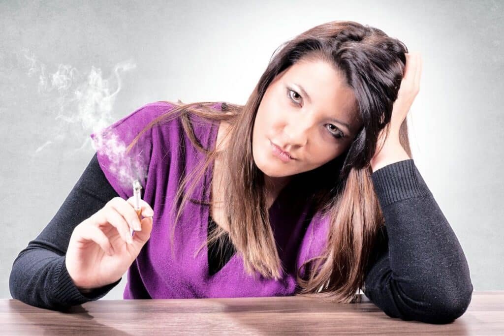 Femme tenant une cigarette à la main, illustrant la dépendance comportementale que l'hypnose aide à déprogrammer pour arrêter de fumer